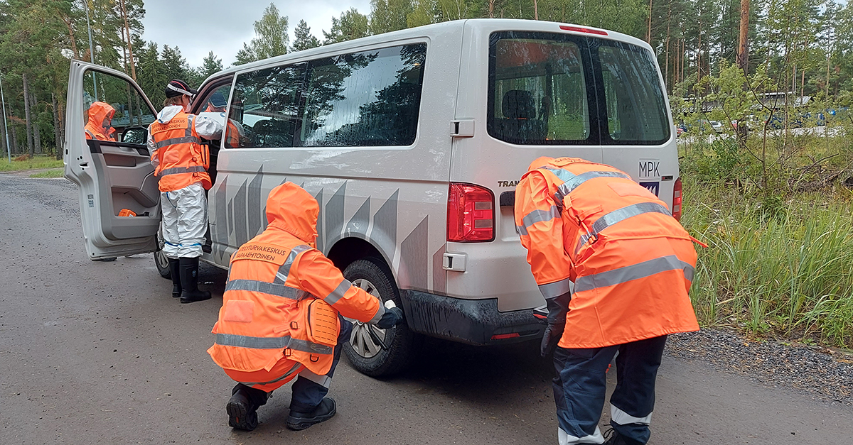 Neljä huomioliiveillä varustettua vapaaehtoista tarkistaa ajoneuvoa.