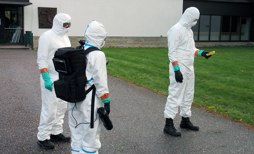 Strålningsmätningsgruppen övar. Personerna bär skyddskläder, masker och strålningsmätare.