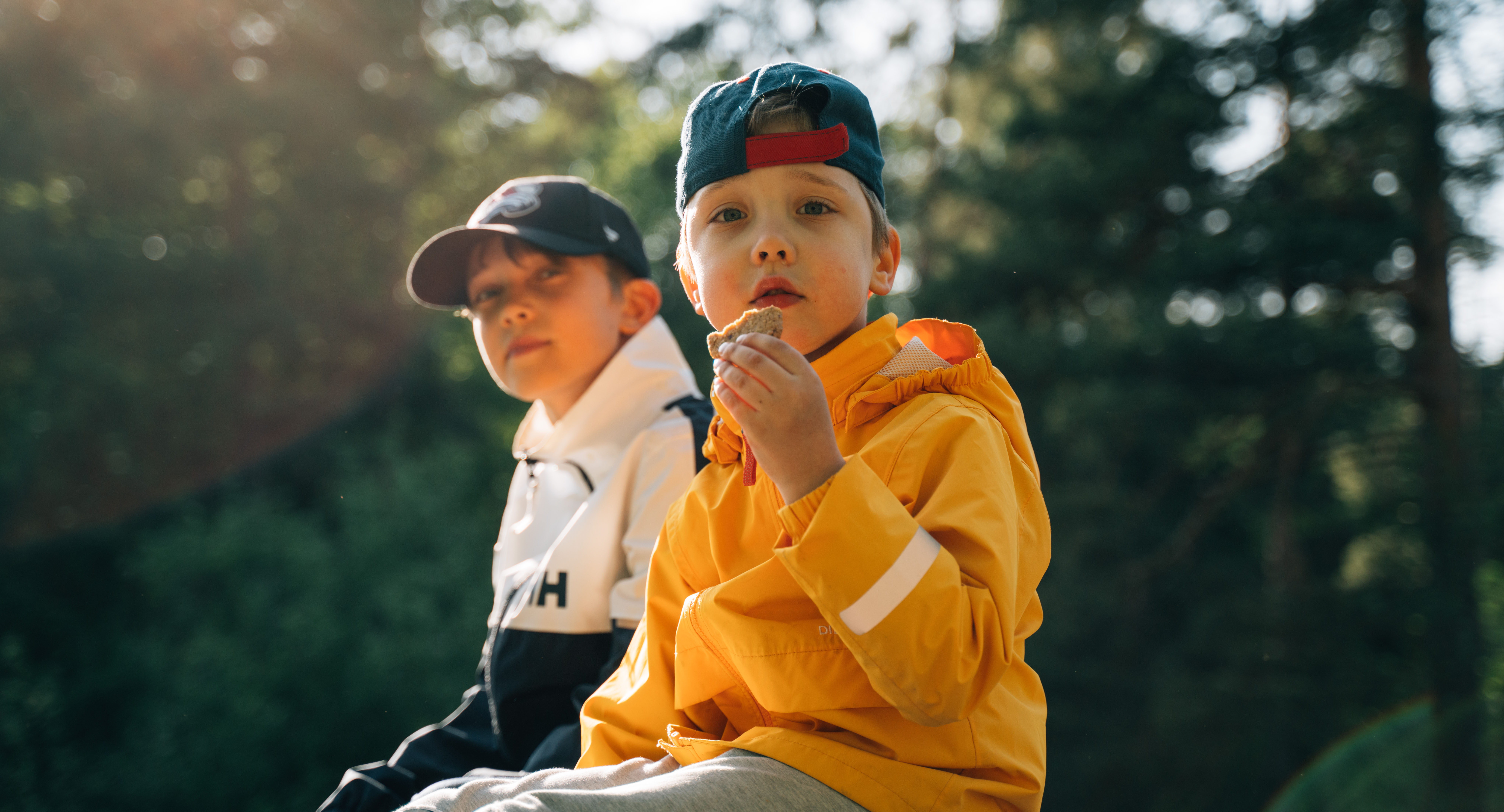 Kaksi lasta istuu aurinkoisella kalliolla